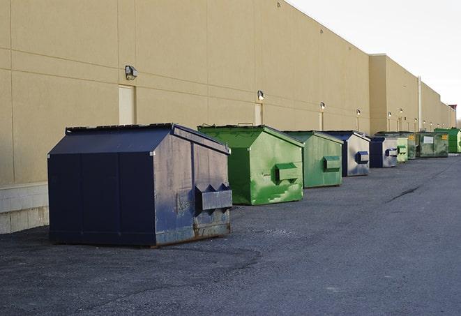 a construction worker unloading debris into a blue dumpster in Euclid OH